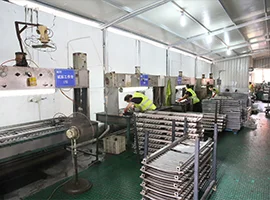 Workers assembling and inspecting metal towel warmers in a factory